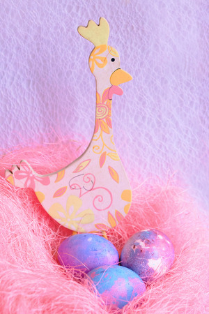 Space galactic Easter eggs in a pink nest next to a chickenの写真素材