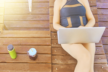 Tourist girl using a laptop on summer vacation in a terrace on the beach.の写真素材