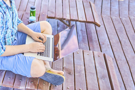 Man with laptop running remotely on colorful beach of island, on the piers.の写真素材