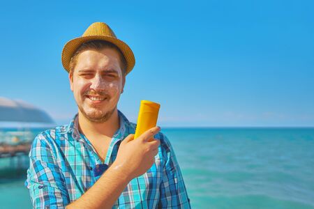 Guy putting on sun protection cream on the face. The man was tanned in the sun on the sea, and he used sunscreen.の写真素材