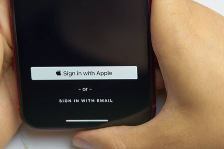 Bishkek, Kyrgyzstan - June 6, 2019: Sign in with Apple Button for your privacy. Man holds a...