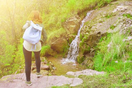 Female hiker walking in mountains forest. A woman with a backpack found a water source in the mountains.の写真素材