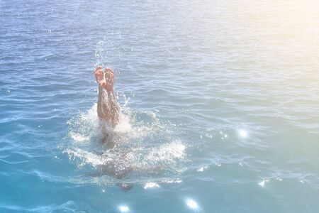 Feet of a man jumping into the ocean. A lot of foam from the waterの写真素材