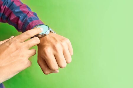 Man wear smart watch in everyday lifestyle with blank screen. Concept for business, multi payment, lifestyle using and other. Smartwatch - modern digital gadget with empty display, copy space. Green backgroundの写真素材