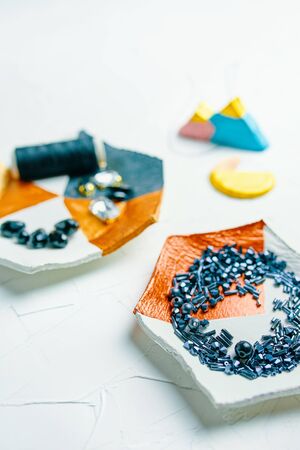 Process of creating jewelry with elements of zircons crystals bugle beads and threads on the tableの写真素材