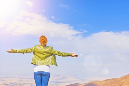 Beauty woman outdoors enjoying nature. A tourist girl on a mountain and looks at the sunrise.の写真素材