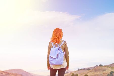 Beauty woman outdoors enjoying nature. Hipster young girl with backpack enjoying sunset on peak of mountain. Tourist traveler on background valley landscape view mockup, sunlight in trip, mock up for text.の写真素材