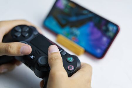 Bishkek, Kyrgyzstan - June 06, 2019: Man playing games on Apple arcade subscription system on ios 13 with sony dualshock gamepadのeditorial素材