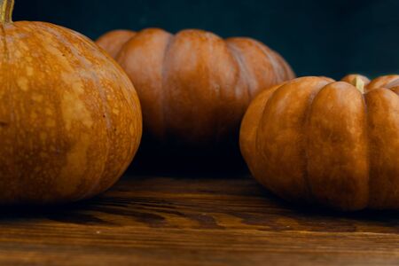 A bunch of pumpkins. A bunch of pumpkins on black wooden rustic table over dark concrete background. With copy space. Vintage retro style. Selective focusの写真素材