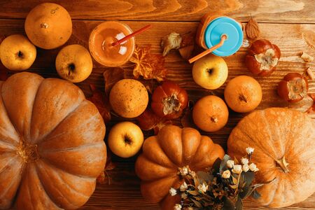 Pumpkins juice in bottles with pumpkins. Two glasses cups of pumpkin juice, pumpkins and fallen ma. Ple leaves on kitchen tableの写真素材