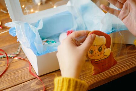 Woman hand packaging christmas gift box. New Year packaging wrapping paper