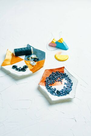 Process of creating jewelry with elements of zircons crystals bugle beads and threads on the tableの写真素材