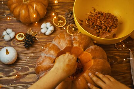 Close-up of Man's hands carve pumpkin for Halloween on wooden rustic table. Halloween autumn concept.の写真素材