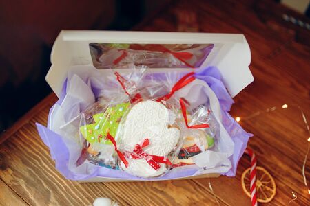 Presenting a christmas gift box - with gingerbread cookie inside. Hands presenting a New Year present - with gingerbread cookie pine tree inside, top viewの写真素材