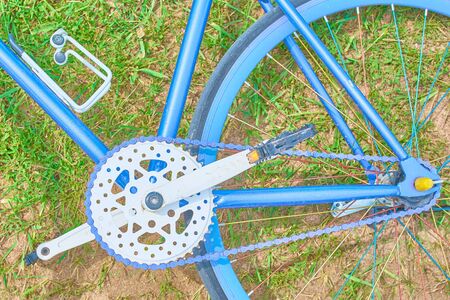 Bright blue bike lying on the grass with sand on a Sunny dayの写真素材