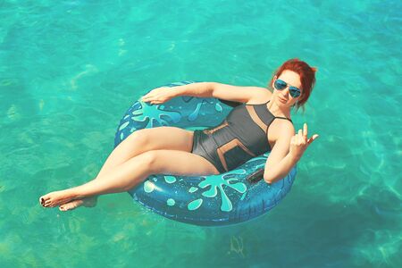 Beautiful young woman relax on inflatable ring in sea waterの写真素材