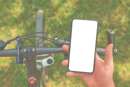 Man with a smartphone on a bike trains on offroad. mock up.の写真素材