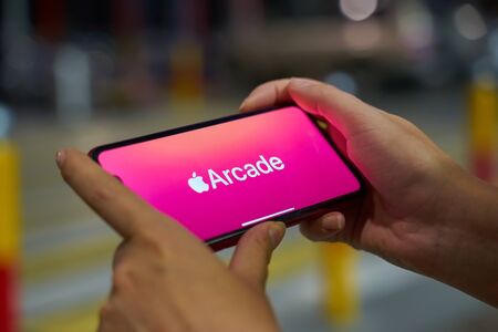Bishkek, Kyrgyzstan - September 19, 2019: Woman holds the new iphone in landscape mode and subscribes to apple arcade with pink backgroundのeditorial素材