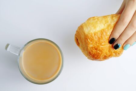 Woman having Breakfast French croissant and coffee on a white tableの写真素材