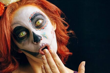 A young woman in day of the dead mask skull face art. Red-head model wear sugar skull makeupの写真素材