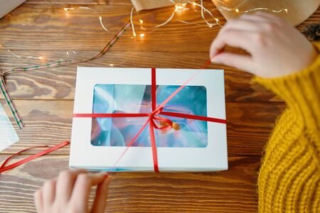 Christmas composition with present box. A Christmas gift box with a red ribbon stands on a wooden table.の写真素材