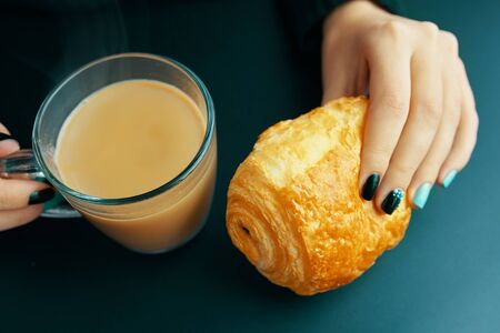 Woman having Breakfast French croissant and coffee on a dark tableの写真素材