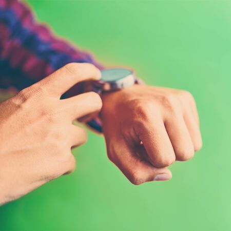 Man wear smart watch in everyday lifestyle with blank screen. Smartwatch - modern digital gadget with empty display, copy space. Green backgroundの写真素材