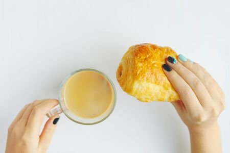 Woman having Breakfast French croissant and coffee on a white tableの写真素材
