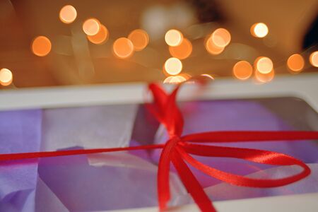 Christmas composition with present box. A Christmas gift box with a red ribbon stands on a wooden table.の写真素材