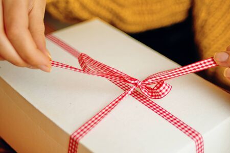 Christmas composition with present box. A Christmas gift box with a red ribbon stands on a wooden table.の写真素材