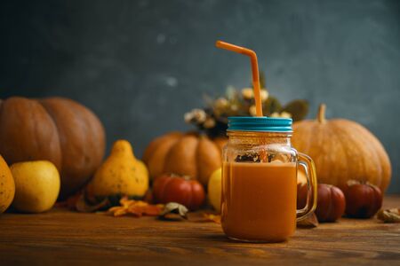 Pumpkins juice in bottles with pumpkins. Glass of fresh pumpkin smoothie on wooden backgroundの写真素材