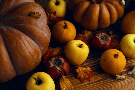 A bunch of pumpkins and apples. Autumn pumpkins with apples on wooden background and leaves. Orange pumpkins on a wooden table in the autumn gardenの写真素材