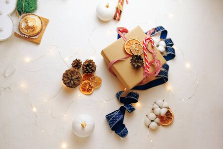 New Year gift box made of ribbon tied. A box for a Christmas gift stands on a white table with a ribbon and down.の写真素材