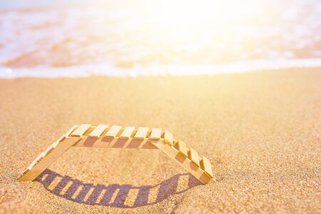 Wooden deckchair on a tropical sand beach. Wooden deckchair on a tropical sand beach overlooking the sea water.の写真素材