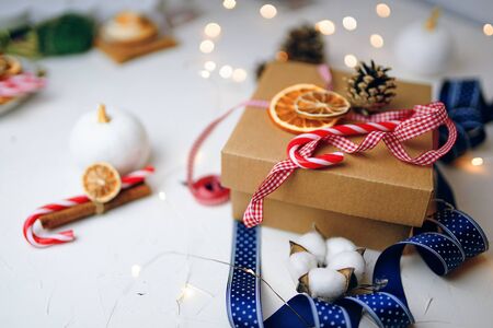New Year gift box made of ribbon tied. The box is on the table with a ribbon and fluff.の写真素材