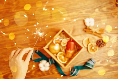 Christmas time. Process of packing gifts for holidays. Woman holds sparklerの写真素材