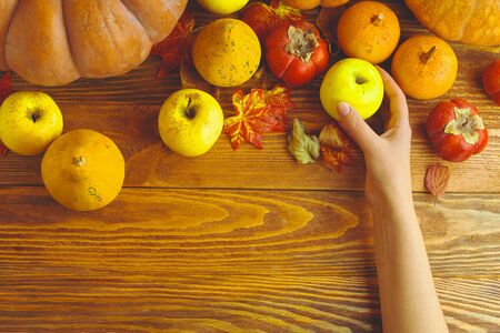 A bunch of pumpkins and apples. Halloween pumpkins on wooden table against dark background.の写真素材
