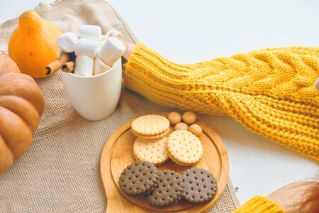 Pumpkin Cookies With Cups Of Coffee. Autumn winter pastries. Cozy atmosphere, warm knitted sweater, girl drink coffee, hands in picture.の写真素材