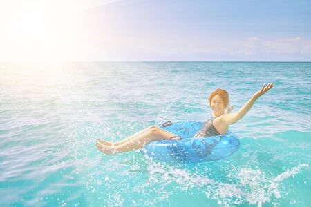 Amazing young woman relax on inflatable ring make water splash in sea waterの写真素材