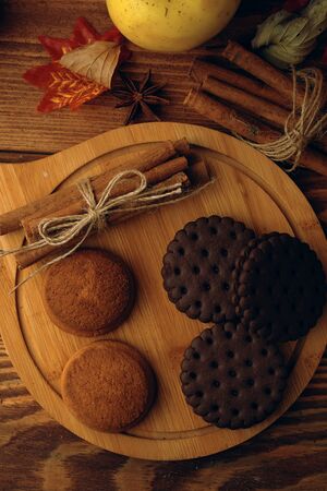 Cookies with pumpkins and apples on the table. Chocolate chip cookies with apples and pumpkins in the background lie on a wooden table.の写真素材