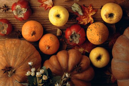 Pumpkins and apples. A bunch of pumpkins and a few apples lie on a wooden table top view.の写真素材