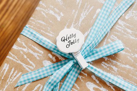 Little tag with Christmas wishes and gifts. Small label on the gift box that says Holly Jolly.の写真素材