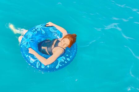 Beautiful young woman relax on blue inflatable ring in sea waterの写真素材