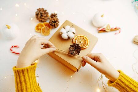 Woman packaging Christmas gift box. Girl packing a box with gifts for Christmas.の写真素材