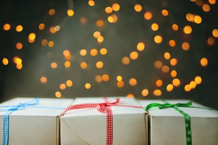 Stack of gift wrapped Christmas presents. The pile of gifts is stacked neatly on the table with a garland in the background. Side view.の写真素材