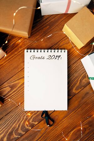 Prepare for Christmas with Notepad and gifts. Notebook with the words Goals 2019 lies on a wooden table.の写真素材