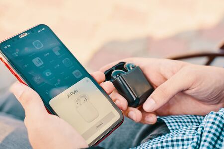 Bishkek, Kyrgyzstan - October 10, 2019: Man holds custom black airpods and connects them to iphone 11のeditorial素材