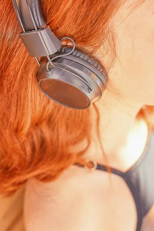 Cute red head woman listening to music at sunny dayの写真素材