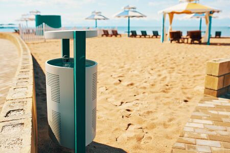 Trashcan on the beach. Iron waste canister, by the sea.の写真素材