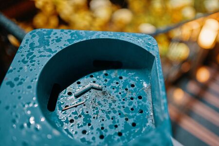 Big ashtray with cigarette butts. Blue can with ashtray.の写真素材